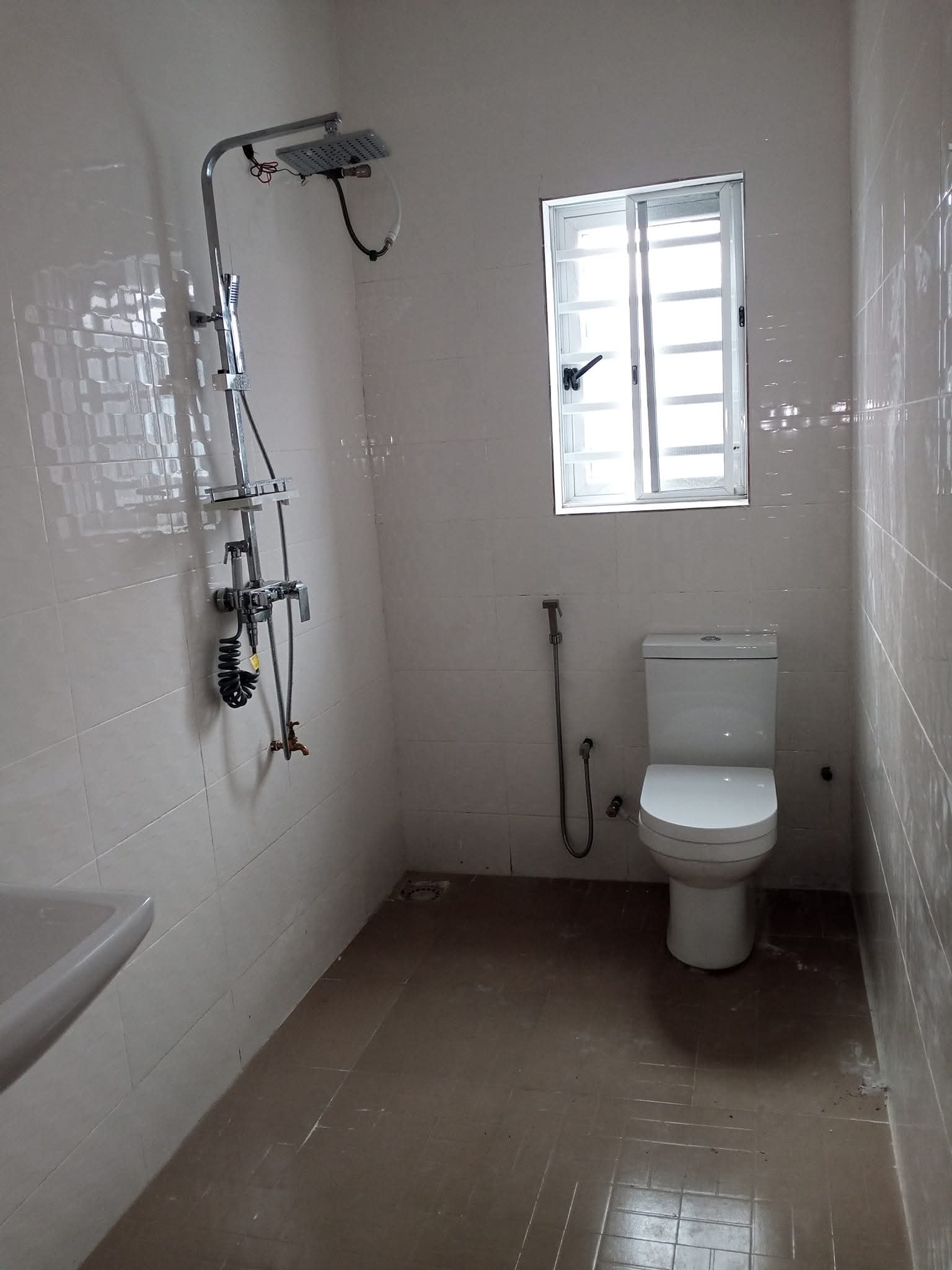 Tiled bathroom with chrome rain-shower column, mixer and close-coupled WC