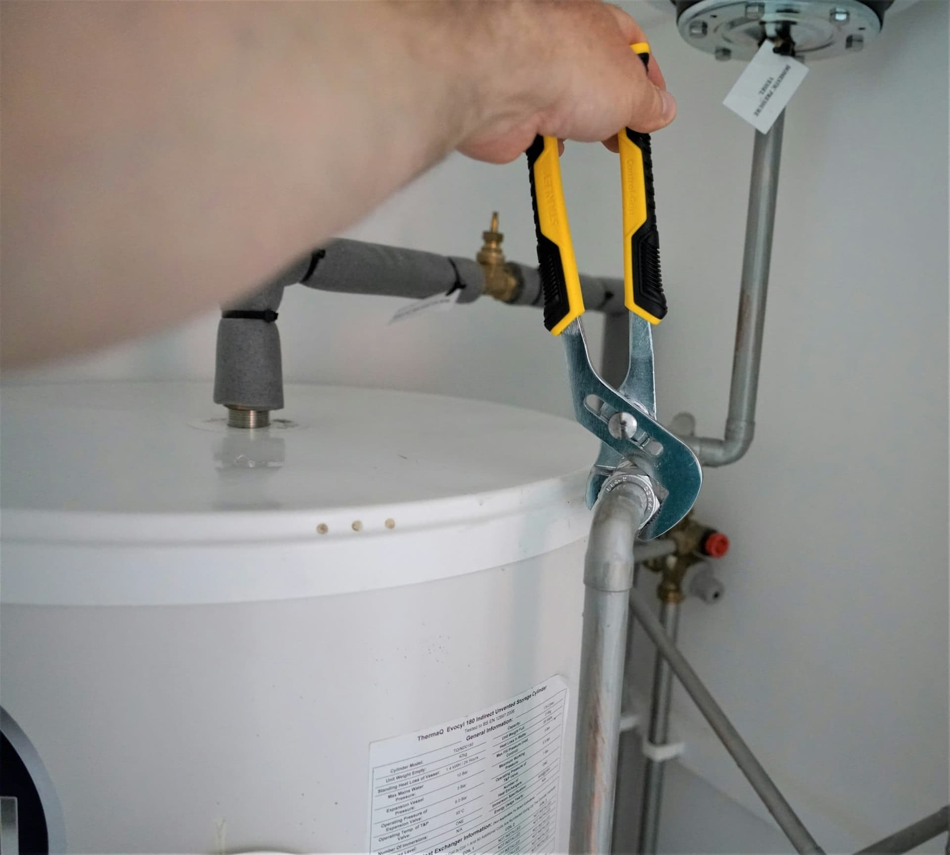Hand holding a yellow and grey plumbing tool
